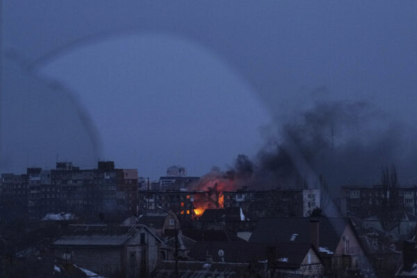 Seen through a broken window, a fire burns at an apartment building after the shelling of a residential district in Mariupol, Ukraine, Friday, March 11, 2022. (AP Photo/Evgeniy Maloletka)
