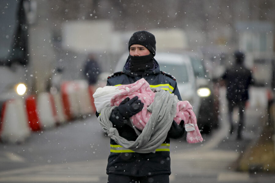 A firefighter holds the baby of a refugee fleeing the conflict from neighbouring Ukraine at the Romanian-Ukrainian border, in Siret, Romania, Monday, March 7, 2022. (AP Photo/Andreea Alexandru)