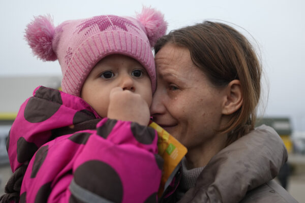A women with a child who fled from the war in Ukraine reacts as they reuniting with their family after crossing the border in Medyka, Poland, Tuesday, March 1, 2022. (AP Photo/Markus Schreiber)