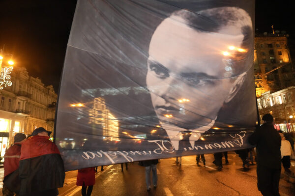 Activists of various nationalist parties carry a portrait of Stepan Bandera during a rally in Kyiv, Ukraine, Saturday, Jan. 1, 2022. The rally was organized to mark the birth anniversary of Stepan Bandera, founder of a rebel army that fought against the Soviet regime and who was assassinated in Germany in 1959. (AP Photo/Efrem Lukatsky)