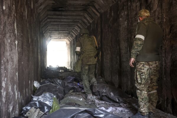 FILE – Servicemen of the Donetsk People’s Republic militia look at bodies of Ukrainian soldiers placed in plastic bags in a tunnel, part of the Illich Iron & Steel Works Metallurgical Plant, the second largest metallurgical enterprise in Ukraine, in an area controlled by Russian-backed separatist forces in Mariupol, Ukraine, Monday, April 18, 2022. On Thursday, April 21, 2022, Russian President Vladimir Putin ordered his forces not to storm the last remaining Ukrainian stronghold in the besieged city of Mariupol but to block it “so that not even a fly comes through.”  (AP Photo/Alexei Alexandrov, File)
