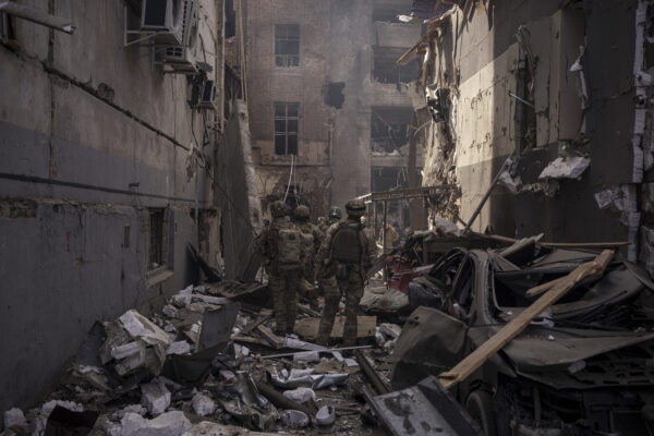 Ukrainian servicemen walk among debris of damaged buildings after a Russian attack in Kharkiv, Ukraine, Saturday, April 16, 2022. (AP Photo/Felipe Dana)