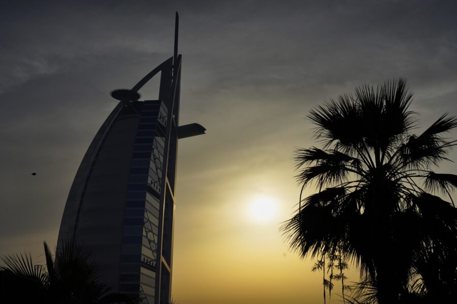 The sun sets behind the Burj al-Arab hotel in Dubai, United Arab Emirates, Friday, April 22, 2022. (AP Photo/Jon Gambrell)