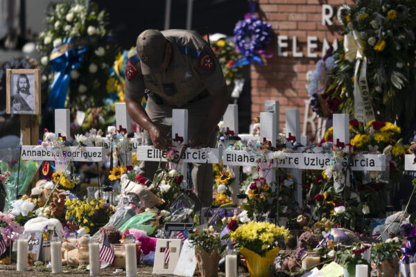 A state trooper places a tiara on a cross honoring Ellie Garcia, one of the victims killed in this week’s elementary school shooting in Uvalde, Texas Saturday, May 28, 2022. (AP Photo/Jae C. Hong)