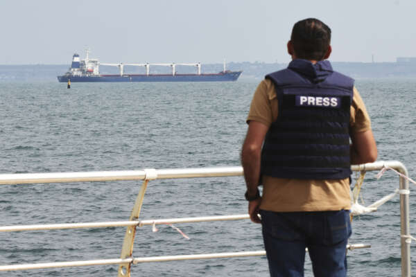 A journalist watches as the bulk carrier Razoni starts its way from the port in Odesa, Ukraine, Monday, Aug. 1, 2022. According to Ukraine’s Ministry of Infrastructure, the ship under Sierra Leone’s flag is carrying 26 thousand tons of Ukrainian corn to Lebanon. The first ship carrying Ukrainian grain set off from the port of Odesa on Monday under an internationally brokered deal and is expected to reach Istanbul on Tuesday, where it will be inspected, before being allowed to proceed. (AP Photo/Michael Shtekel)