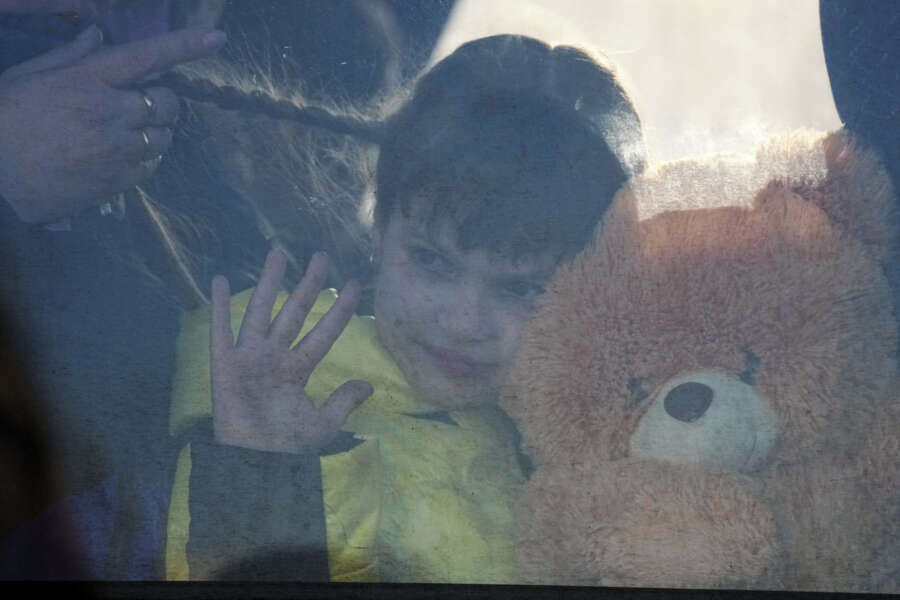 A refugee girl waves from a bus after fleeing the war from neighbouring Ukraine at the border crossing in Medyka, southeastern Poland, on Sunday, March 27, 2022. More than 3.7 million people have fled the war so far, Europe’s largest exodus since World War II. (AP Photo/Sergei Grits)