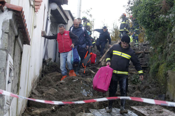Rescuers help people reach their homes after heavy rainfall triggered landslides that collapsed buildings, in Casamicciola, on the southern Italian island of Ischia, Monday, Nov. 28, 2022. Authorities said that the landslide that early Saturday destroyed buildings and swept parked cars into the sea left seven people dead and 5 missing. (AP Photo/Salvatore Laporta) 

Associated Press/LaPresse