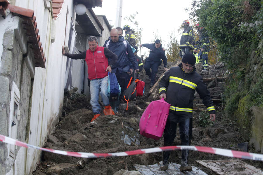 Rescuers help people reach their homes after heavy rainfall triggered landslides that collapsed buildings, in Casamicciola, on the southern Italian island of Ischia, Monday, Nov. 28, 2022. Authorities said that the landslide that early Saturday destroyed buildings and swept parked cars into the sea left seven people dead and 5 missing. (AP Photo/Salvatore Laporta) 

Associated Press/LaPresse