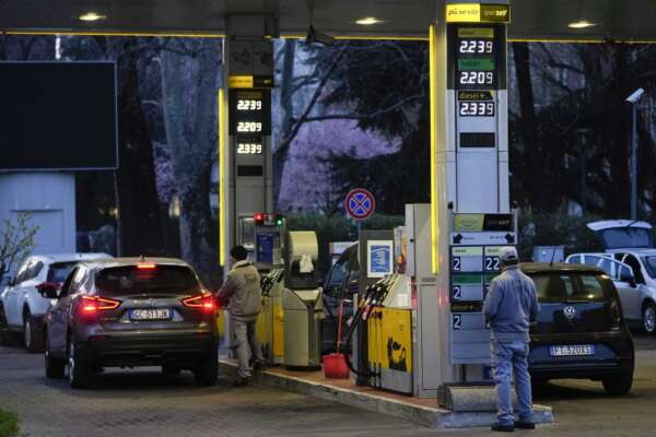 A gas station attendant changes fuel prices on a board at a gas station in Milan, Italy, Thursday, March 10, 2022. Car fuel price in Italy recently exceeded the 2.00 euros per liter threshold due to the turmoil on the international oil market caused by the war in Ukraine, and on Thursday morning drivers found a new record high at the gas stations with fuel touching 2.40 euros per liter records. (AP Photo/Luca Bruno)
