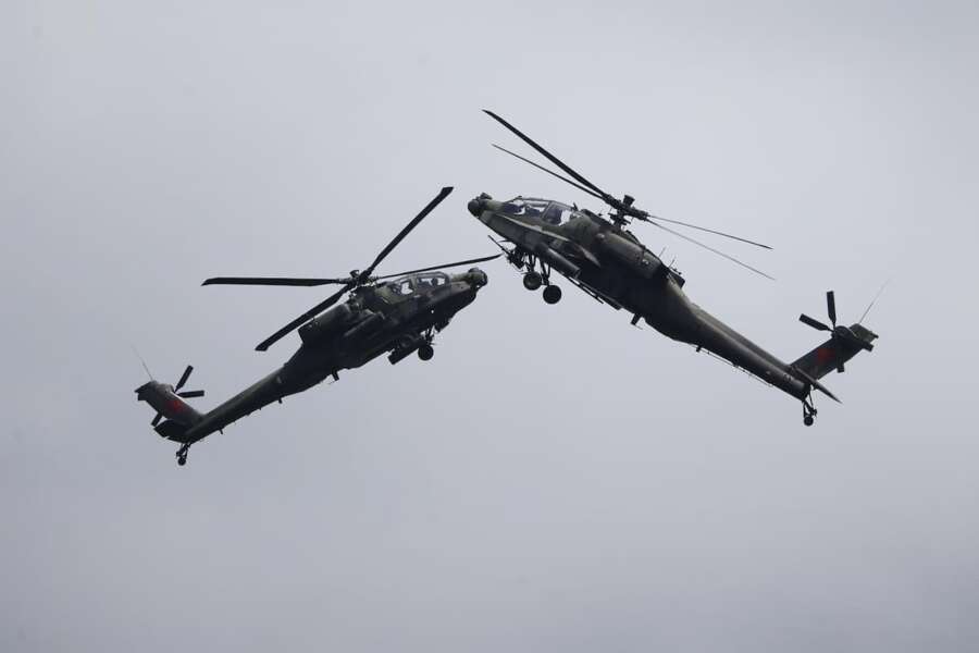 A pair of Republic of Singapore Air Force (RSAF) AH-64D Apache attack helicopters perform aerial maneuvers during the Singapore Airshow 2022 at Changi Exhibition Centre in Singapore, Tuesday, Feb. 15, 2022. (AP Photo/Suhaimi Abdullah)