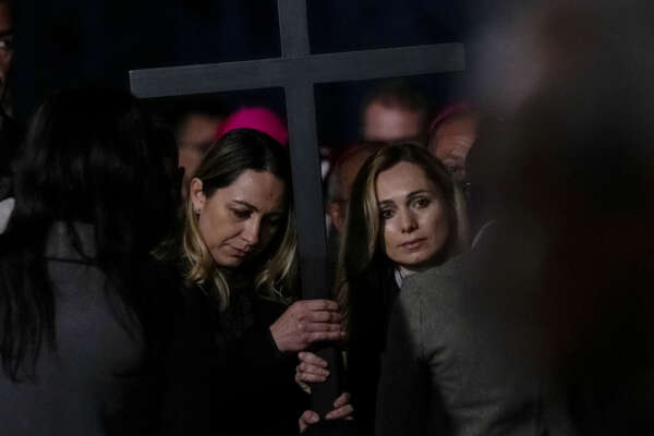 Two nurses, Albina from Russia, right, and Irina, from Ukraine hold the cross as they take part in the Via Crucis (Way of the Cross) torchlight procession presided by Pope Francis on Good Friday in front of Rome’s Colosseum, in Rome, Friday, April 15, 2022. (AP Photo/Gregorio Borgia)
