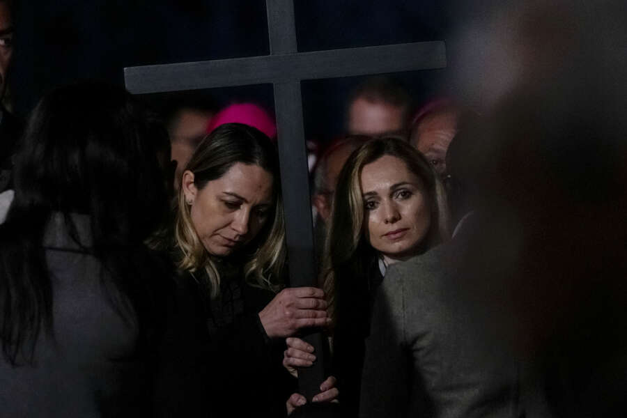 Two nurses, Albina from Russia, right, and Irina, from Ukraine hold the cross as they take part in the Via Crucis (Way of the Cross) torchlight procession presided by Pope Francis on Good Friday in front of Rome’s Colosseum, in Rome, Friday, April 15, 2022. (AP Photo/Gregorio Borgia)