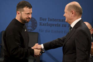 Ukrainian President Volodymyr Zelenskyy, left, and German Chancellor Olaf Scholz, right, shake hands during the award ceremony of the Charlemagne Prize in Aachen, Germany, Sunday, May 14, 2023. Zelenskyy is in Aachen to receive the International Charlemagne Prize, awarded to him and the people of Ukraine. (Ina Fassbender/Pool Photo via AP)