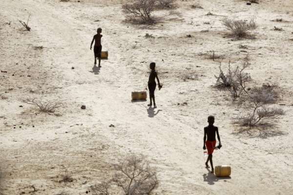 Ragazzini tirano contenitori d’acqua mentre tornano alle loro capanne da un pozzo nel villaggio di Ntabasi in mezzo a una siccità a Samburu East, in Kenya,