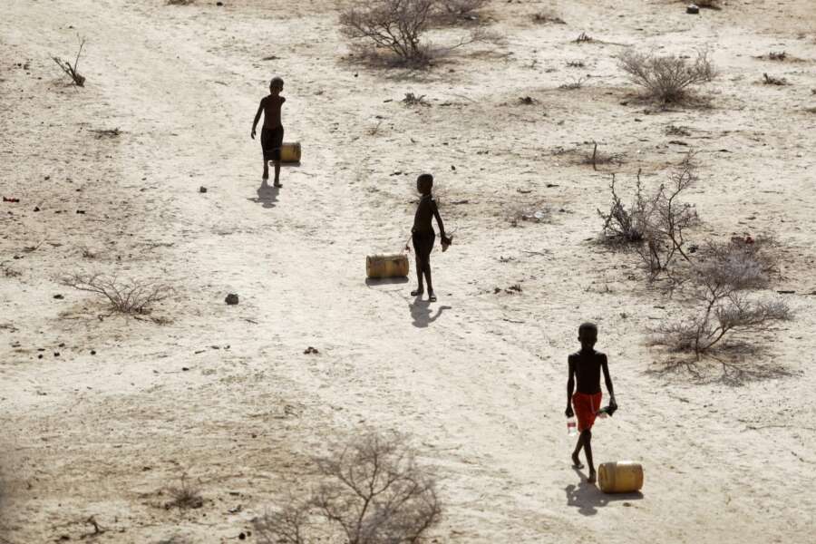 Ragazzini tirano contenitori d’acqua mentre tornano alle loro capanne da un pozzo nel villaggio di Ntabasi in mezzo a una siccità a Samburu East, in Kenya,