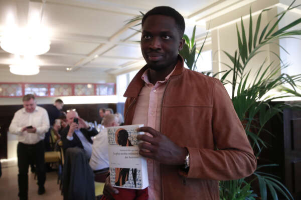Senegalese novelist Mohamed Mbougar Sarr holds a copy of his book after he was awarded with France’s prestigious Goncourt literary prize Wednesday, Nov. 3, 2021 in Paris. Mohamed Mbougar Sarr, 31, won the prize for his novel “The most secret memory of men” ((La plus secrete memoire des Hommes). ( (AP Photo/Lewis Joly)