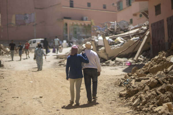 People walk through the wreckage caused by the earthquake, in the town of Amizmiz, near Marrakech, Morocco, Sunday, Sept. 10, 2023. An aftershock rattled Moroccans on Sunday as they mourned victims of the nation’s strongest earthquake in more than a century and sought to rescue survivors while soldiers and aid workers raced to reach ruined mountain villages. (AP Photo/Mosa’ab Elshamy)