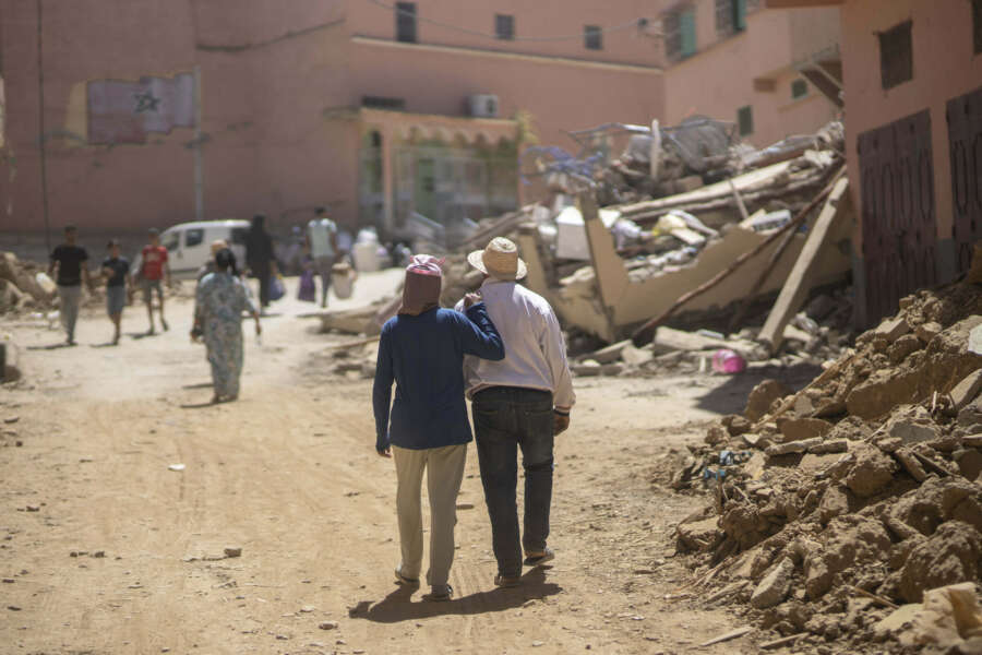 People walk through the wreckage caused by the earthquake, in the town of Amizmiz, near Marrakech, Morocco, Sunday, Sept. 10, 2023. An aftershock rattled Moroccans on Sunday as they mourned victims of the nation’s strongest earthquake in more than a century and sought to rescue survivors while soldiers and aid workers raced to reach ruined mountain villages. (AP Photo/Mosa’ab Elshamy)