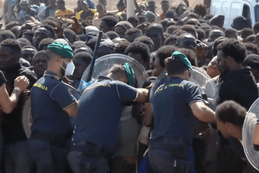 Lampedusa, migranti contro Gdf si buttano in acqua per lasciare il molo: in centinaia bloccati da ore | Neonato morto, isolani aiutano barca sugli scogli. È il caos