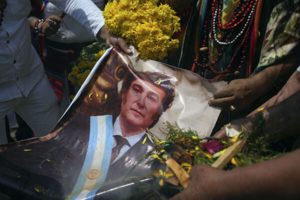 Shamans hold a photo of Argentina’s President Javier Milei as they perform an annual ritual to predict political and social issues for the new year, on the top of San Cristobal hill in Lima, Peru, Wednesday, Dec. 27, 2023. (AP Photo/Guadalupe Pardo)