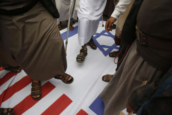 Houthi supporters trample on representation of the U.S and Israeli flags during a rally marking eight years for a Saudi-led coalition, Friday, March 26, 2023, in Sanaa, Yemen. (AP Photo/Hani Mohammed)