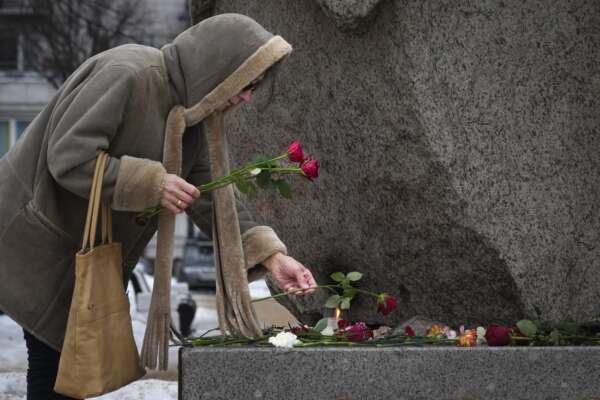A woman pays tribute to Alexei Navalny at the monument, a large boulder from the Solovetsky islands, where the first camp of the Gulag political prison system was established in St. Petersburg, Russia, on Wednesday, Feb. 21, 2024. Russians across the vast country streamed to ad-hoc memorials with flowers and candles to pay tribute to Alexei Navalny, the most famous Russian opposition leader and the Kremlin’s fiercest critic. Russian officials reported that Navalny, 47, died in prison on Friday, Feb. 16, 2024. (AP Photo/Dmitri Lovetsky)