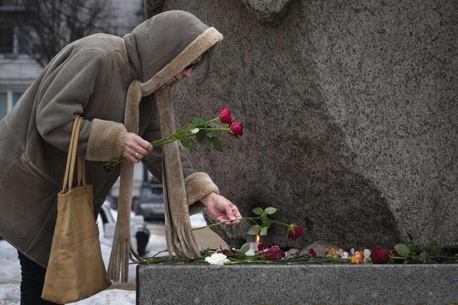 A woman pays tribute to Alexei Navalny at the monument, a large boulder from the Solovetsky islands, where the first camp of the Gulag political prison system was established in St. Petersburg, Russia, on Wednesday, Feb. 21, 2024. Russians across the vast country streamed to ad-hoc memorials with flowers and candles to pay tribute to Alexei Navalny, the most famous Russian opposition leader and the Kremlin’s fiercest critic. Russian officials reported that Navalny, 47, died in prison on Friday, Feb. 16, 2024. (AP Photo/Dmitri Lovetsky)