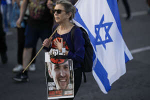A woman walks during a protest against Israeli Prime Minister Benjamin Netanyahu’s government and call for the release of hostages held in the Gaza Strip by the Hamas militant group outside of the Knesset, Israel’s parliament, in Jerusalem, Sunday, March 31, 2024. Tens of thousands of Israelis gathered outside the parliament building in Jerusalem on Sunday, calling on the government to reach a deal to free dozens of hostages held by Hamas and to hold early elections. (AP Photo/Leo Correa)