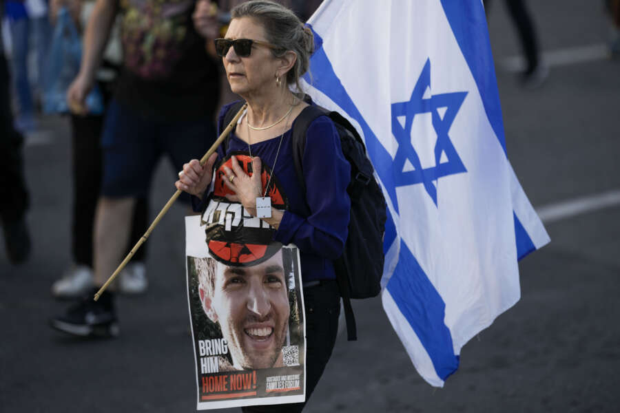 A woman walks during a protest against Israeli Prime Minister Benjamin Netanyahu’s government and call for the release of hostages held in the Gaza Strip by the Hamas militant group outside of the Knesset, Israel’s parliament, in Jerusalem, Sunday, March 31, 2024. Tens of thousands of Israelis gathered outside the parliament building in Jerusalem on Sunday, calling on the government to reach a deal to free dozens of hostages held by Hamas and to hold early elections. (AP Photo/Leo Correa)