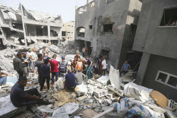Palestinians look at the destruction after an Israeli strike on a residential building in Nuseirat Refugee Camp, Gaza Strip, Sunday, May 19, 2024. (AP Photo/Ismael Abu Dayyah)