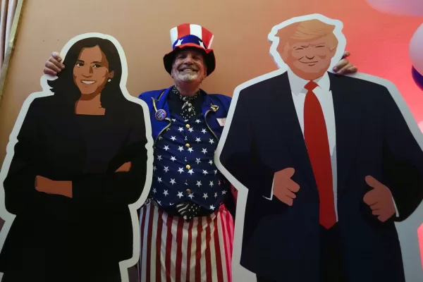 U.S. Consulate General Services Officer Timothy Lockwood poses with cardboards of Kamala Harris and Donald Trump during the Election Night event in Milan, Italy, Tuesday, Nov. 5, 2024. (AP Photo/Luca Bruno)