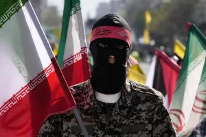 A member of the Iranian paramilitary Basij force holds an Iranian flag as he covers her face in the Palestinian and Lebanese militants style in an annual rally to mark Quds Day, or Jerusalem Day, to support the Palestinians in Tehran, Iran, Friday, April 5, 2024. In the rally in Tehran, thousands attended a funeral procession for the seven Revolutionary Guard members killed in an airstrike widely attributed to Israel that destroyed Iran’s Consulate in the Syrian capital on Monday. (AP Photo/Vahid Salemi) A member of the Iranian paramilitary Basij force holds an Iranian flag as he covers her face in the Palestinian and Lebanese militants style in an annual rally to mark Quds Day, or Jerusalem Day, to support the Palestinians in Tehran, Iran, Friday, April 5, 2024. In the rally in Tehran, thousands attended a funeral procession for the seven Revolutionary Guard members killed in an airstrike widely attributed to Israel that destroyed Iran’s Consulate in the Syrian capital on Monday. (AP Photo/Vahid Salemi)