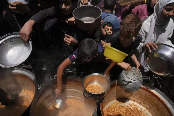 Palestinians receive donated food at a community kitchen in Beit Lahia, northern Gaza Strip, Saturday, May 3, 2025. (AP Photo/Jehad Alshrafi)