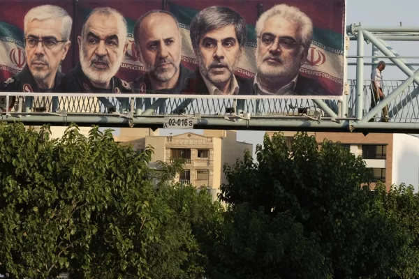 A man walks past a billboard displaying images of top Iranian commanders and scientists killed in Israeli strikes early Friday, in Tehran, Iran, Friday, June 13, 2025. (AP Photo/Vahid Salemi)