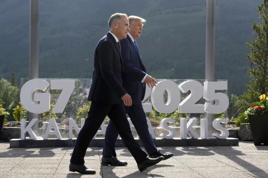 Canadian Prime Minister Mark Carney, left, walks with President Donald Trump before the family photograph during the G7 Summit in Kananaskis, Alberta, Monday, June 16, 2025. (Adrian Wyld/The Canadian Press via AP)