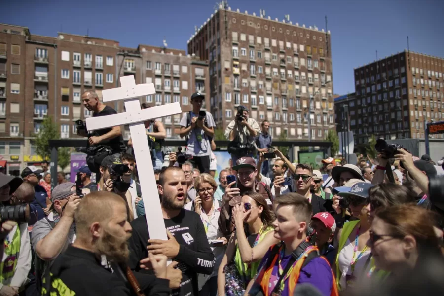 People holding a cross and religious books walk among participants in the Pride march in Budapest, Hungary, Saturday, June 28, 2025. (AP Photo/Rudolf Karancsi)