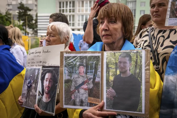 People hold photos of their missing relatives during a POW exchange between Russia and Ukraine, in Chernyhiv region, Ukraine, Thursday, June 19, 2025. (AP Photo/Dan Bashakov)