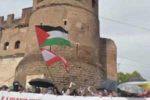 MANIFESTANTI MANIFESTAZIONE PRO PALESTINA BANDIERA PALESTINA STRISCIONE FERMIAMO IL GENOCIDIO