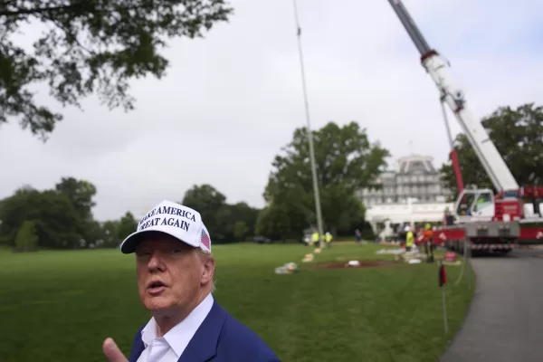 President Donald Trump speaks with reporters as a flag pole is installed on the South Lawn of the White House, Wednesday, June 18, 2025, in Washington. (AP Photo/Evan Vucci)