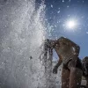 People stand in the fountain in the Lustgarten (pleasure garden) at the Berlin Cathedral in Berlin, Germany, Wednesday, July 2, 2025. (Michael Kappeler/dpa via AP)