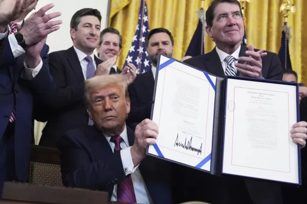 President Donald Trump holds up the signed document after signing the GENIUS Act, a bill that regulates stablecoins, a type of cryptocurrency, in the East Room of the White House, Friday, July 18, 2025, in Washington. (AP Photo/Evan Vucci)