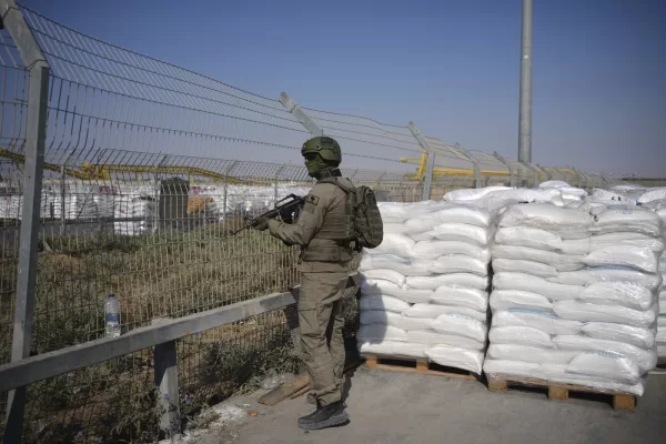 An Israeli soldier stands beside humanitarian aid packages awaiting pickup on the Palestinian side of the Kerem Shalom crossing in the Gaza Strip, Thursday, July 24, 2025. during a media tour organized by the Israeli army. (AP Photo/Ohad Zwigenberg)