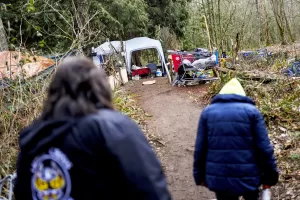 Rachel Cooper, 70, who says she was introduced to fentanyl by her kids, walks back to her tent with Lummi Nation crisis outreach supervisor Evelyn Jefferson, at left, at a longstanding homeless encampment near Walmart, Thursday, Feb. 8, 2024, in Bellingham, Wash. The Lummi Nation declared a state of emergency due to the fentanyl crisis in 2023. Washington State tribal leaders are urging state lawmakers to pass a bill that would send at least $7.75 million in funding to tribal nations to help them stem a dramatic rise in opioid overdose deaths. (AP Photo/Lindsey Wasson)