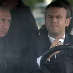 FILE – French President Emmanuel Macron, right, drives an electric golf car with Russian President Vladimir Putin in the garden of the Versailles Palace following their meeting in Versailles, near Paris, France, Monday, May 29, 2017. (Alexei Nikolsky/Sputnik, Kremlin Pool Photo via AP, File)