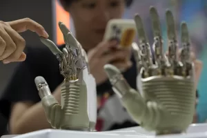 A visitor touches a humanoid robot hand on display at an AI exhibition booth during the 2024 The World Artificial Intelligence Conference (WAIC) & High-Level Meeting on Global AI Governance with the themed “Governing AI for Good and for All” at the Shanghai Expo Center Multifunction Hall in Shanghai China, Thursday, July 4, 2024. (AP Photo/Andy Wong)