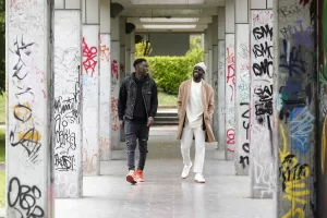 Author and screenwriter Antonio Dikele Distefano, right, and actor Giuseppe Dave Seke walk in Milan, Italy, Tuesday, April 27, 2021. The Netflix series “Zero,” which premiered globally last month, is the first Italian TV production to feature a predominantly black cast, a bright spot in an otherwise bleak television landscape where the persistent use of racist language and imagery in Italy is sparking new protests. (AP Photo/Antonio Calanni)
