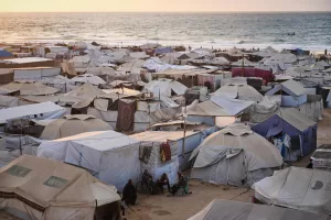 Displaced Palestinians sit by their tent in Muwasi, an area that Israel has designated as a safe zone, in Khan Younis southern Gaza Strip, Thursday, Sept. 25, 2025. (AP Photo/Jehad Alshrafi)