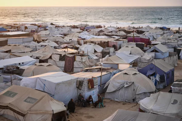 Displaced Palestinians sit by their tent in Muwasi, an area that Israel has designated as a safe zone, in Khan Younis southern Gaza Strip, Thursday, Sept. 25, 2025. (AP Photo/Jehad Alshrafi)