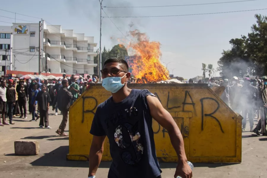 An protester watches police near burning barricades during a protest calling for the president to step down in Antananarivo, Madagascar, Thursday, Oct. 9, 2025. (AP Photo/Alexander Joe)