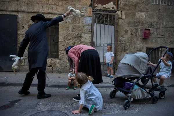 An ultra-Orthodox Jewish man swings a chicken over a woman’s head in Jerusalem, Tuesday, Sept. 30, 2025, as part of the Kaparot ritual days ahead of the Jewish holiday of Yom Kippur. (AP Photo/Ohad Zwigenberg)